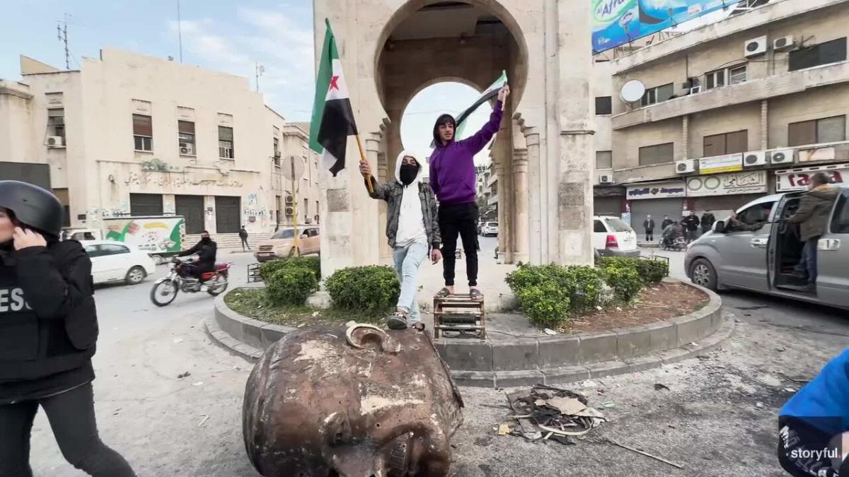 Syrians Pose Next to Head of Toppled Statue of Hafez al-Assad in Hama